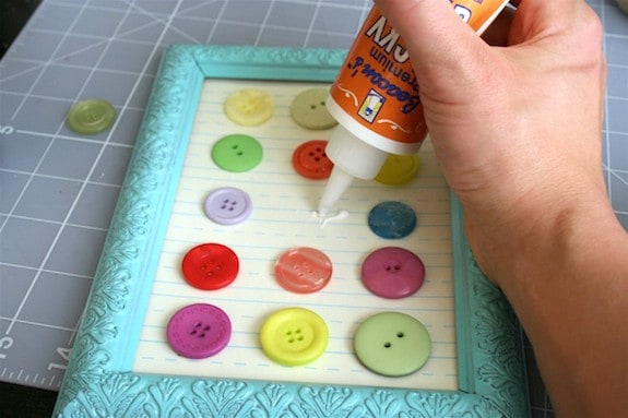 Adding buttons to the scrapbook paper with craft glue