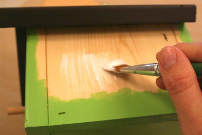 Painting Mod Podge on the side of the birdhouse