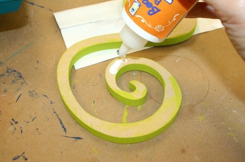 Applying craft glue to the back of the wood letter S