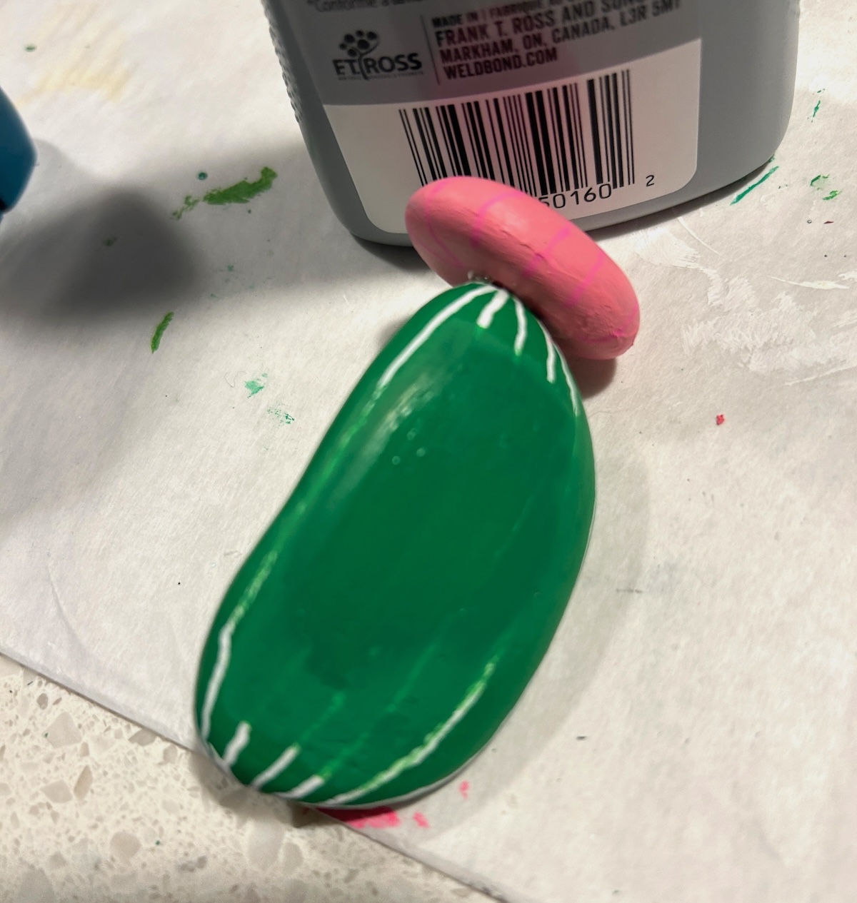 painting over the white lines on a rock with green paint