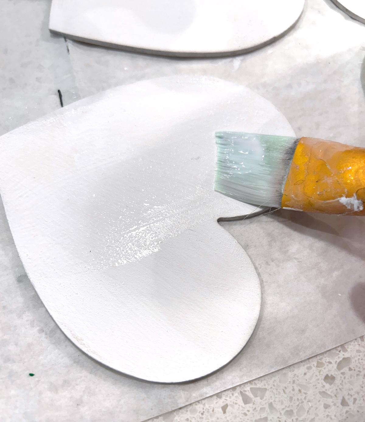 painting the white hearts with Mod Podge