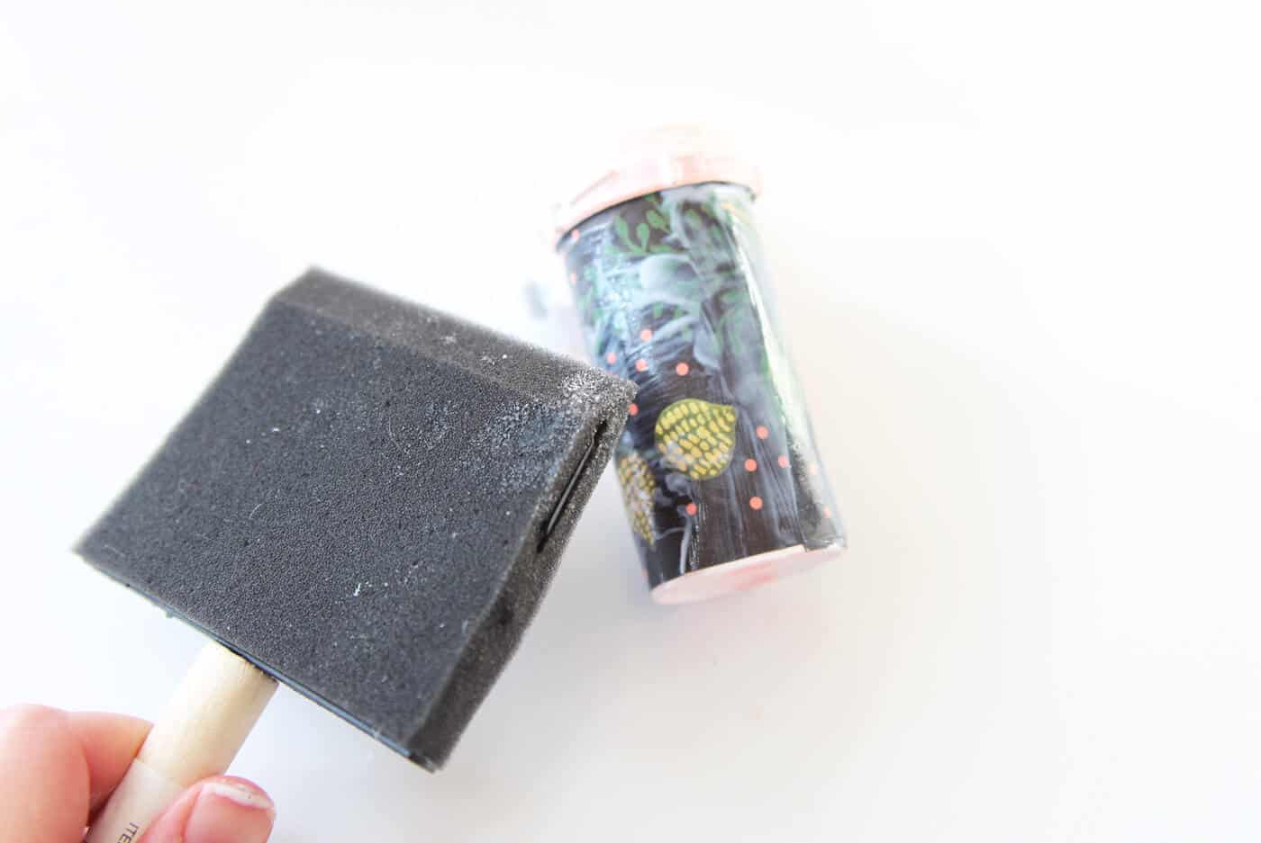 Applying Mod Podge to the paper on the bottle
