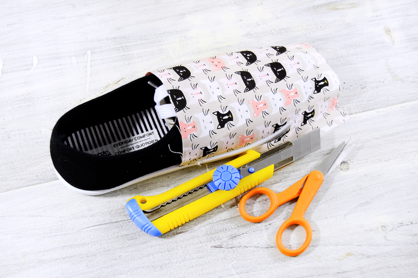 Trimming the fabric around the edge of teh shoe with a razor blade