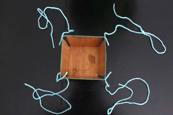 Yarn tied to four corners of a berry basket
